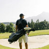 Ein Golfer steht auf dem Golfplatz Schwarzsee-Reith bei Kitzbühel mit einer Golftasche und blickt auf die sanften Hügel im Hintergrund.