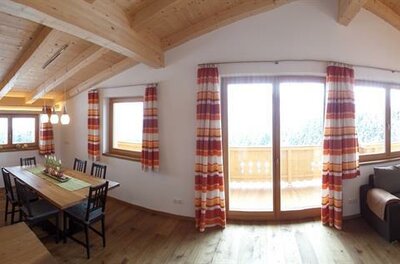Moderner Wohn- und Essbereich mit Holzbalkendecke, Küchenzeile, Esstisch und Ecksofa.