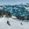 Zwei Skifahrer fahren über eine schneebedeckte Piste im Skigebiet Kitzbühel, umgeben von Bergen und Nadelwäldern.