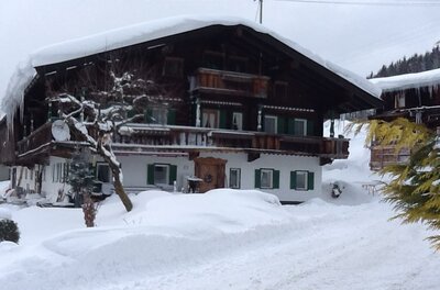 Branderhof in Jochberg Traditionelles Alpenhaus aus Holz und Stein mit schneebedecktem Dach im Winter.