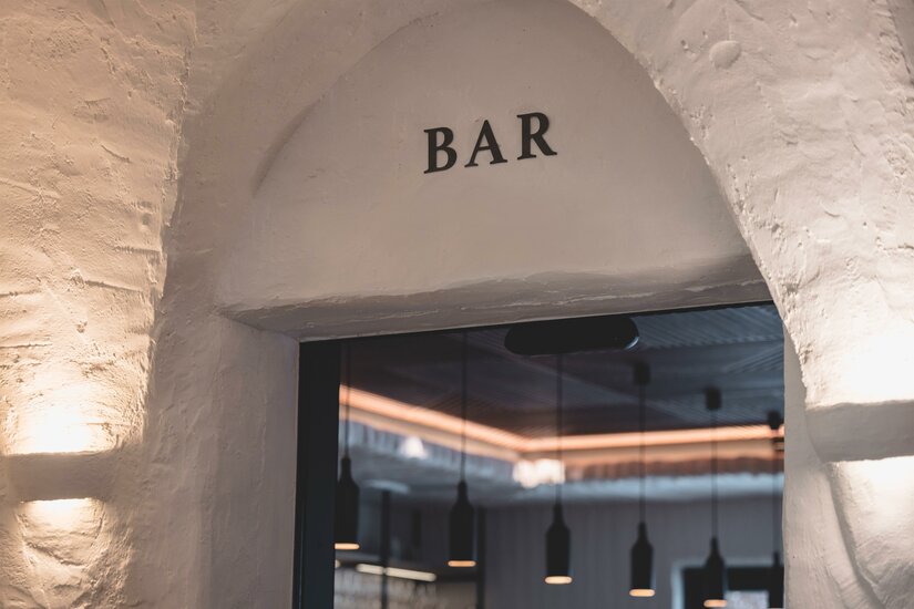 Eingang zur Mocking Bar Eingangsbereich einer Bar mit Rundbogen und weißem Mauerwerk.