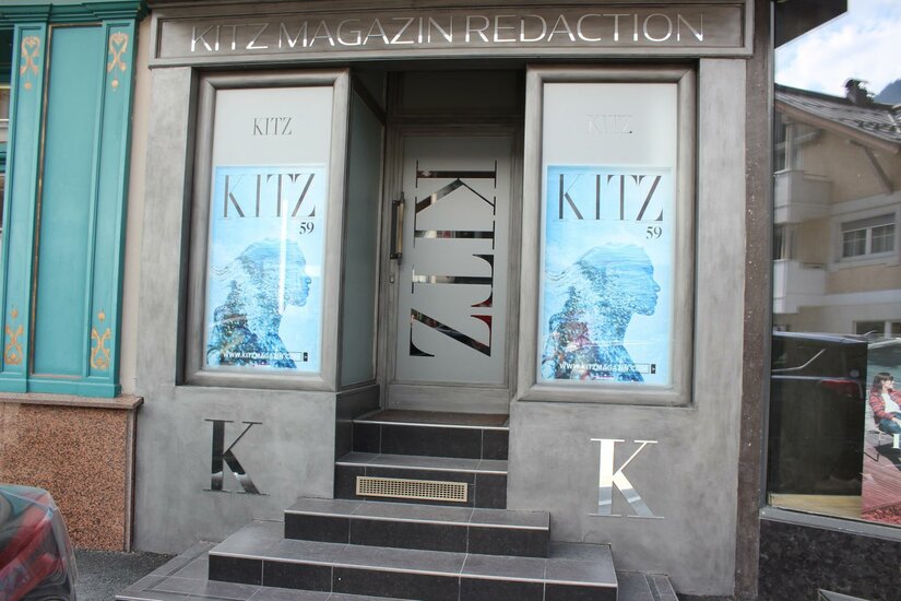 KitzMagazin Ein modernes Geschäft mit Glaseingang und auffälligen Werbeflächen. Die Fassade ist in Grautönen gehalten und zeigt das Logo "KITZ".