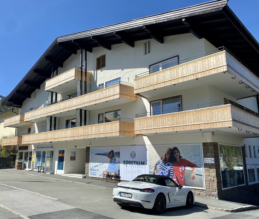 Mehrstöckiges Gebäude mit Holzbalkonen und Ladenzeile im Erdgeschoss in Kitzbühel.