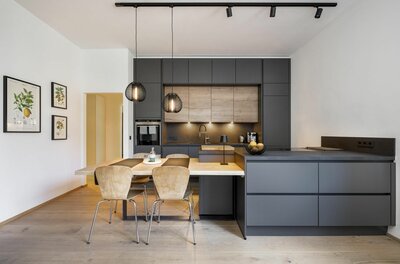 Küche im Apartment 1919 Moderne Einbauküche in Anthrazit und Holzoptik mit angrenzendem Esstisch und vier Stühlen.