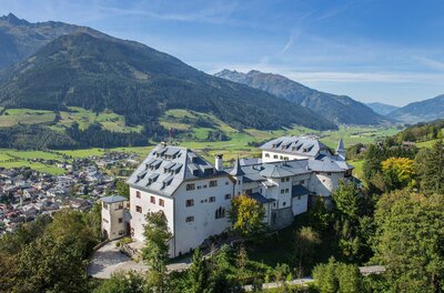 Schloss Mittersill Luftaufnahme von Schloss Mittersill vor bewaldeten Bergen und einer Ortschaft im Tal.