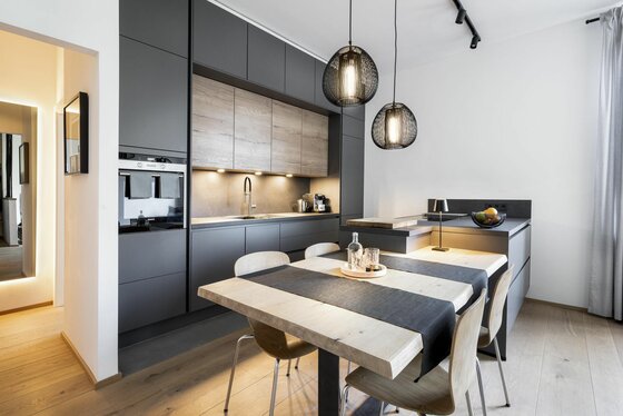 Moderne Küche in Anthrazit und Holzoptik mit Esstisch und zwei Pendelleuchten.