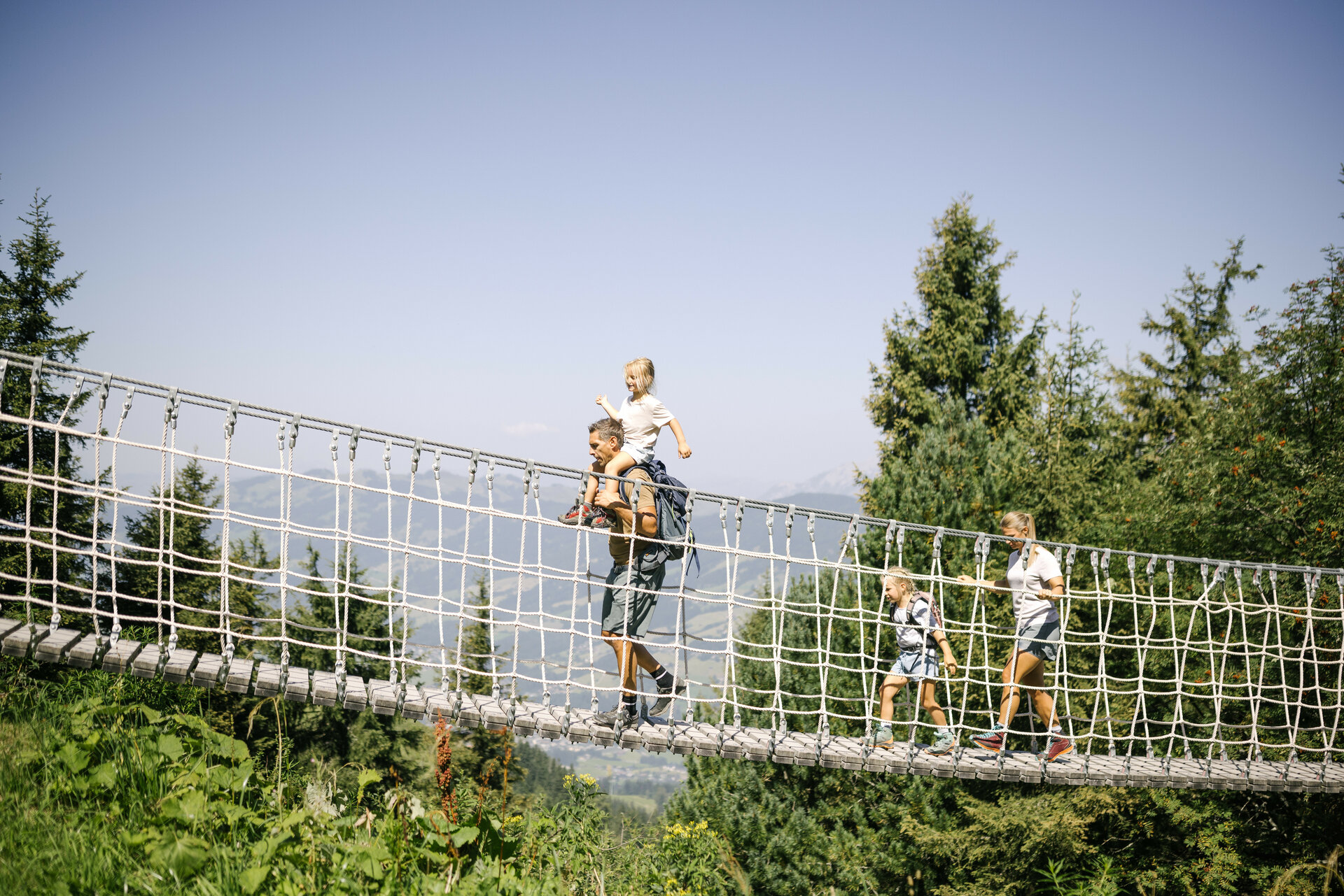 A family crosses a rope bridge