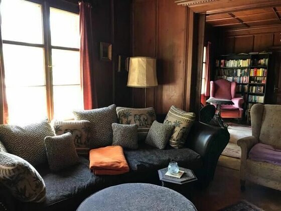 Rustikales Wohnzimmer mit dunklem Sofa, gemusterten Kissen und Holzvertäfelung an den Wänden.