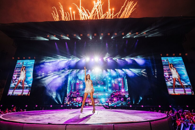 Sängerin Andrea Berg auf einer beleuchteten Open-Air-Bühne mit Feuerwerk im Hintergrund.