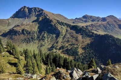 Gipfelpanorama des Geißsteins Blick auf den felsigen Gipfel des Geißsteins mit bewaldeten Hängen unter blauem Himmel.