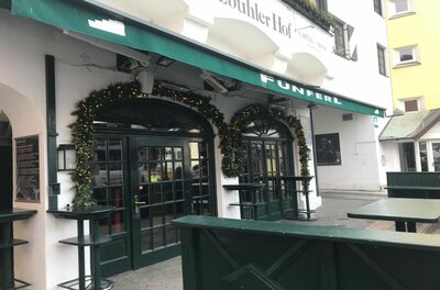 Eingang Fünferl Eingangsbereich des Lokals Fünferl mit grüner Markise und weihnachtlicher Girlande über den Rundbogentüren.