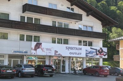 Sportalm Outlet Kitzbühel Außenansicht des Sportalm Outlets in einem mehrstöckigen Gebäude mit Parkplatz davor.