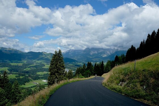 Bergstraße am Kitzbüheler Horn Asphaltierte Bergstraße am Kitzbüheler Horn mit Blick auf bewaldete Hänge und Berge unter bewölktem Himmel.