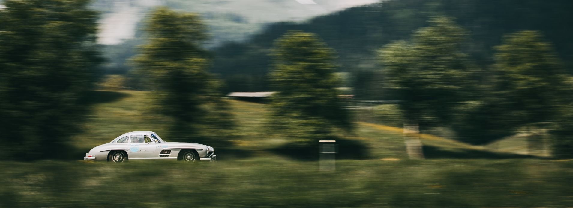 Rallye in den Alpen ein weißes Auto fährt vor dem Bergmassiv des Wilden Kaisers