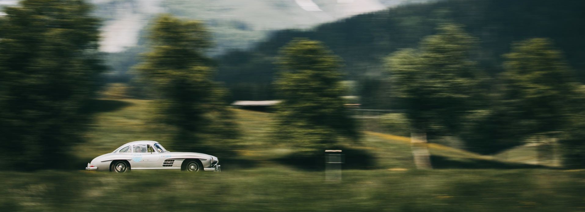 Rally in the Alps a white car drives in front of the Wilder Kaiser mountain massif