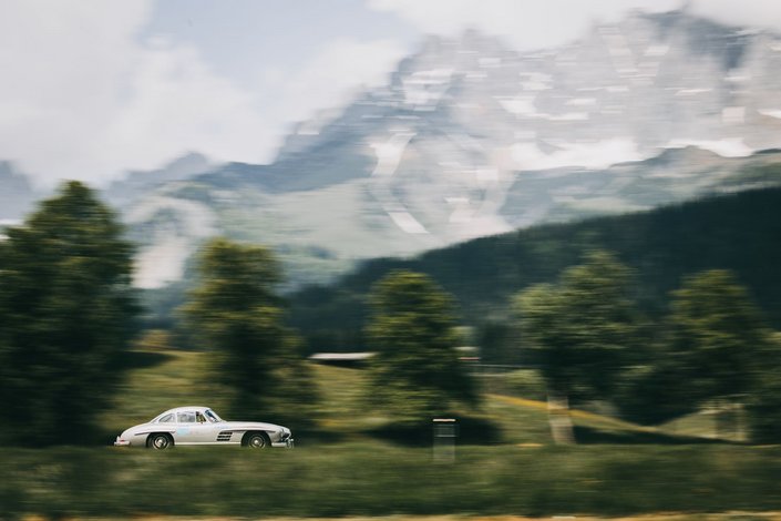 A white vintage racing car against the mountain backdrop of the Wilder Kaiser in summer