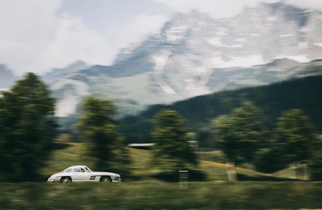 [Translate to EN:] Ein weißes Auto vor der Kulisse der Berglandschaft des Wilden Kaisers