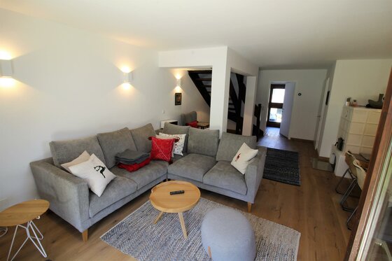 Modernes Wohnzimmer mit grauem Ecksofa, Holztisch und Teppich in einer Ferienwohnung.