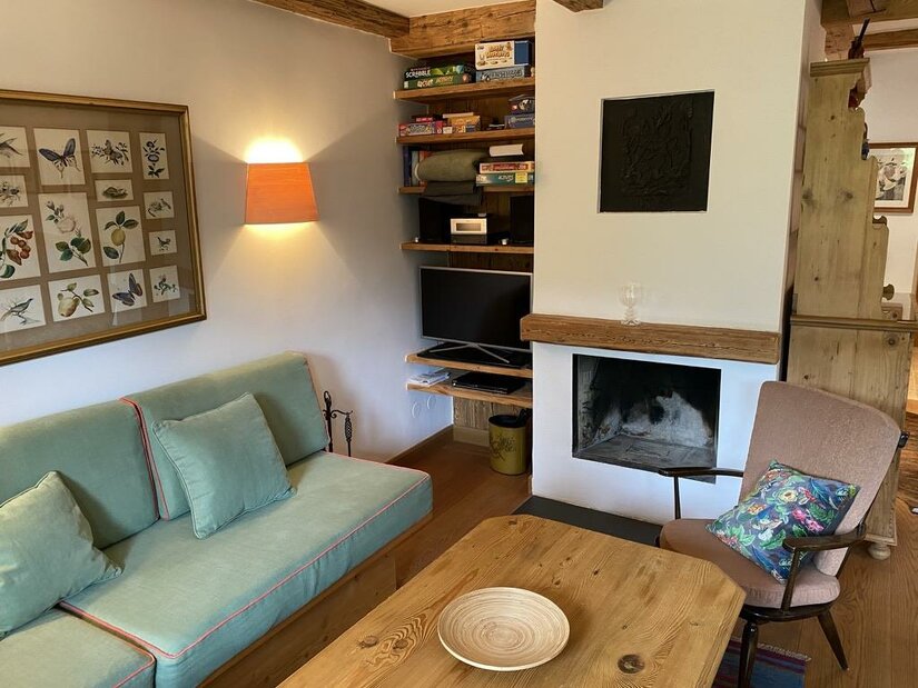 Wohnzimmer mit Kamin Wohnbereich mit grünem Sofa, Holztisch und offenem Kamin in einer Ferienwohnung.