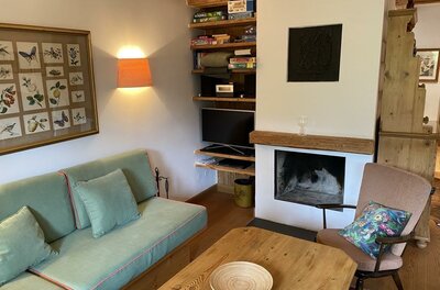 Wohnzimmer mit Kamin Wohnbereich mit grünem Sofa, Holztisch und offenem Kamin in einer Ferienwohnung.