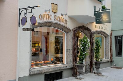 Außenansicht des Optikergeschäfts Optic Schott mit Schaufenster und dekorativem Brillenschild.