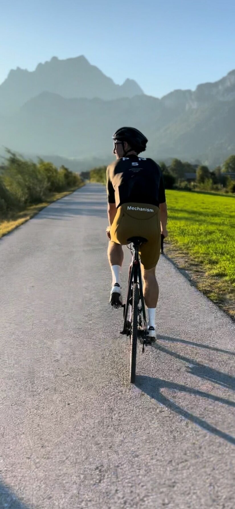 Rennradfahren im Pillerseetal Ein Rennradfahrer von hinten auf einem asphaltierten Weg vor einer Bergkulisse.