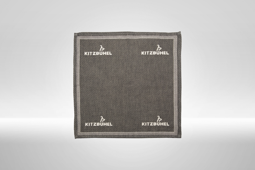 Eine graue Stoffserviette mit dem Logo von Kitzbühel, elegant und schlicht, ideal für festliche Anlässe oder den Alltag.