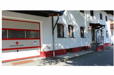 Weißes Gebäude mit Garagentor des Roten Kreuzes und Treppenaufgang.