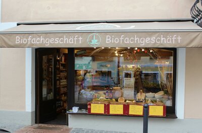 GXUND Natur und Reform Bioladen Außenansicht eines Biofachgeschäfts mit Markise, Schaufenster und Warenpräsentation im Eingangsbereich.