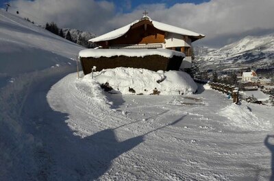 Haus Schuh im Winter Verschneites Holzhaus mit Satteldach an einem präparierten Winterweg in den Bergen.