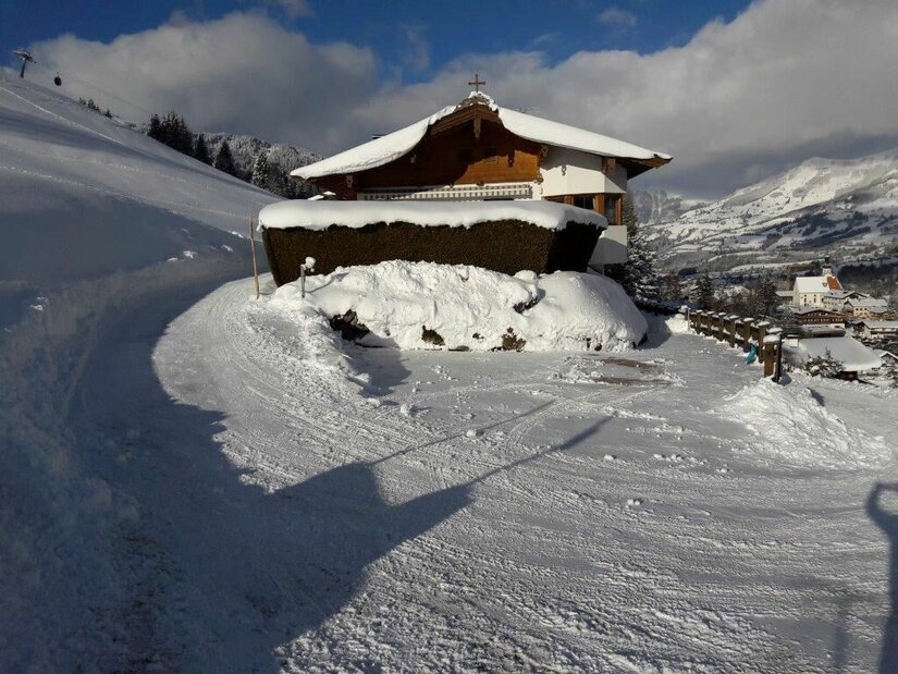 Haus Schuh im Winter Verschneites Holzhaus mit Satteldach an einem präparierten Winterweg in den Bergen.