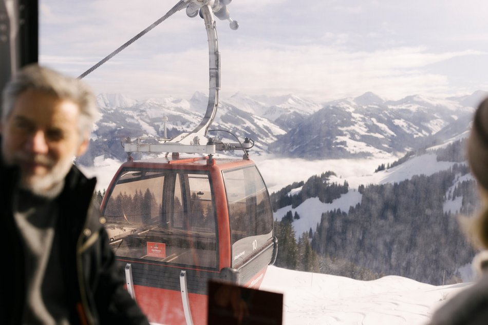Ein Herr in der Gondel mit weißen Bergen im Hintergrund