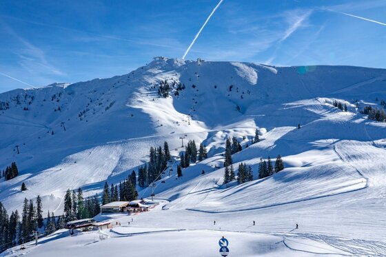Skigebiet Hahnenkamm im Winter Verschneites Skigebiet mit Skipisten, Liftanlagen und einer Berghütte unter blauem Himmel.