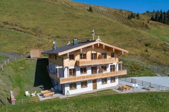 Chalet Rettenstein & Bärenbadkogel Dreistöckiges Chalet aus Holz und weißem Putz vor einem grünen Grashang.