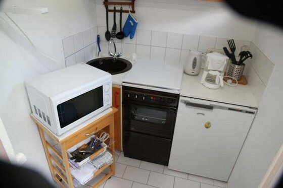 Küche im Haus Jasmin Kleine Küchenzeile mit Mikrowelle, Herd, Spüle und Kaffeemaschine.
