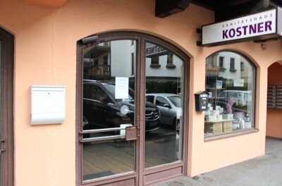 Kostner Ein Geschäft mit einer Eingangstür und Fenstern. Über der Tür steht der Schriftzug "KOSTNER".
