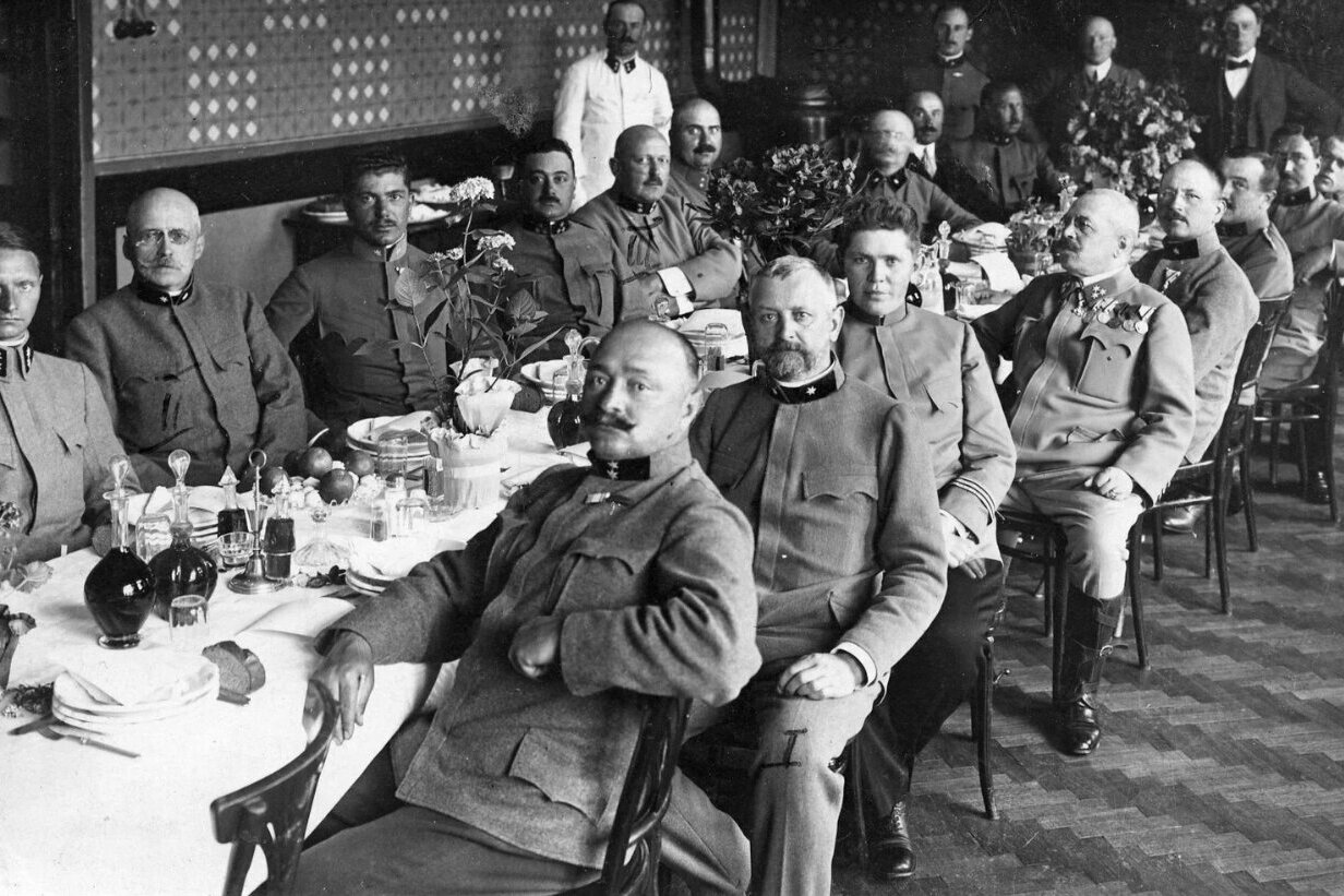 Männer in Uniform der Nationalsozialisten sitzen an einem gedeckten Tisch