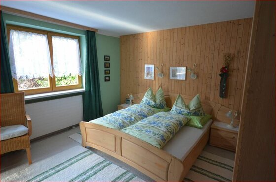 Doppelzimmer im Haus Schneerose Doppelbett aus Holz in einem Zimmer mit Holzvertäfelung und Fenster.