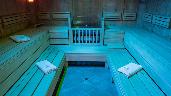 Eine moderne Sauna mit hellblauen Beleuchtungseffekten. Die Holzbank ist sauber und lädt zur Entspannung ein.