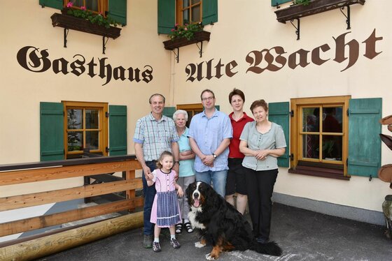 Gastgeber Gasthof Alte Wacht Fünf Erwachsene, ein Kind und ein Berner Sennenhund vor dem Gasthaus Alte Wacht.