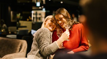 Zwei Freundinnen trinken Wein an der Bar