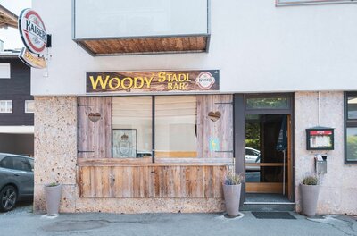 Woody's Stadl Bar Außenansicht der Woody's Stadl Bar mit Holzverkleidung, Herz-Ausschnitten und Firmenschild.