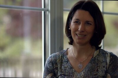 Dr. med. univ. Iris Prethaler Porträt einer lächelnden Frau mit dunklen Haaren vor einem Fenster.