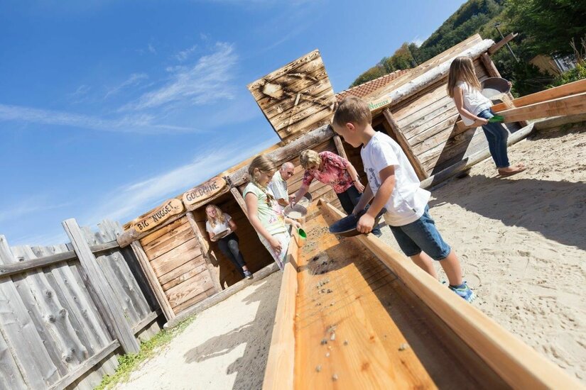 Wasserspielplatz im Edelsteinpark Kinder spielen an einer hölzernen Wasser- und Sandrinne im Edelsteinpark.