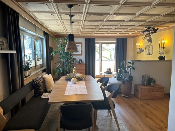 Wohnraum im Haus Egger Moderner Essbereich mit Holztisch, gepolsterter Sitzbank und Kassettendecke aus hellem Holz.