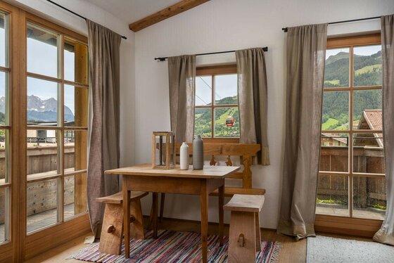 Sitzecke im Asten Apartment Rustikale Sitzecke aus Holz mit Tisch und Bänken vor Fenstern mit Bergblick.