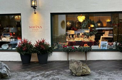 Schaufenster des Geschäfts Sofina in Kitzbühel mit weihnachtlicher Dekoration und beleuchteter Außenwand.