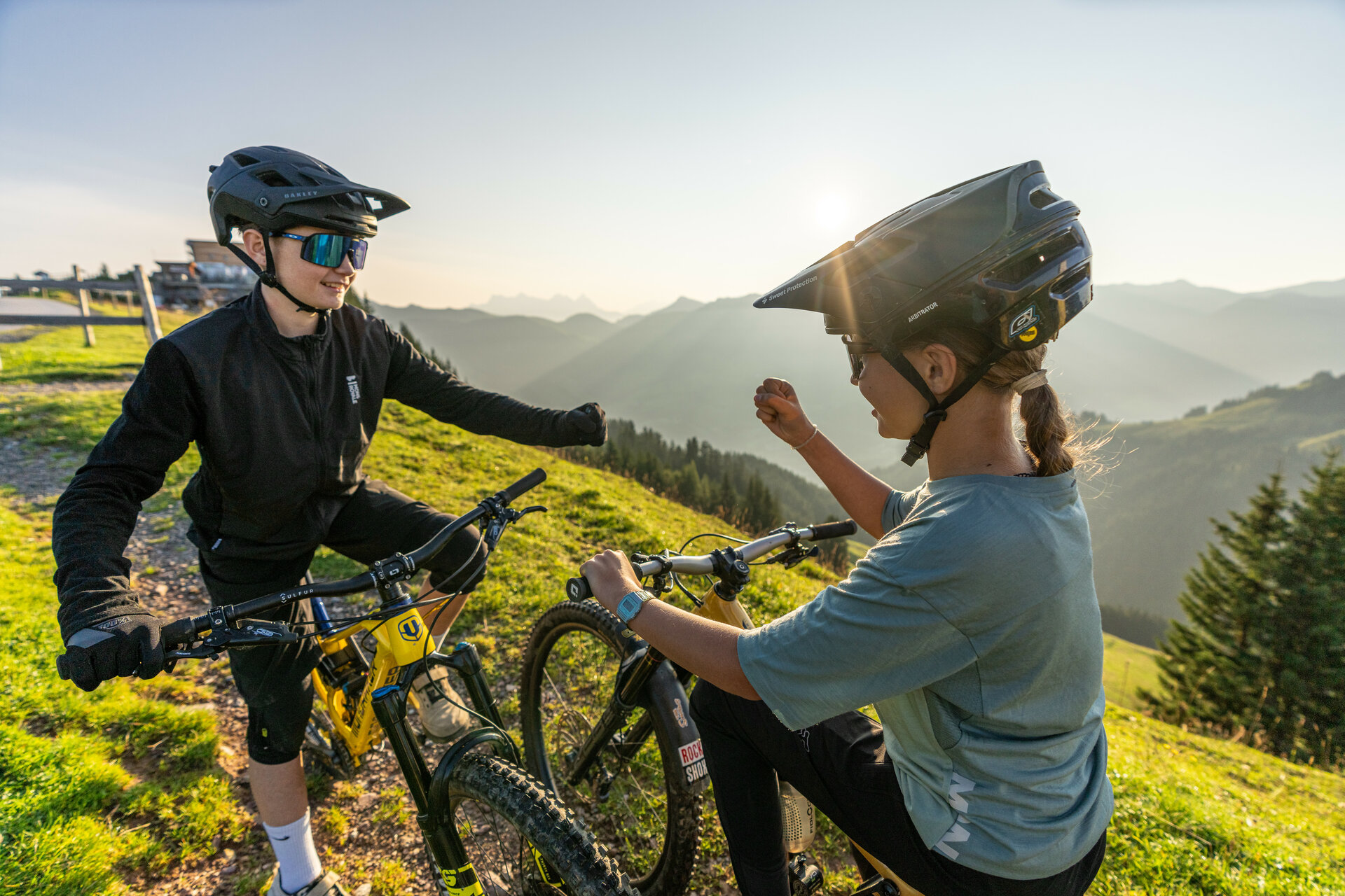 Zwei junge Mountainbiker spielen Schere, Stein, Papier am Start der 360 Flow Trails, um zu entscheiden, wer zuerst den Hahnenkamm Trail fährt.