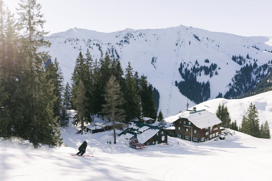 Eine Ein Skifahrer und die Piste mit Schneeabdrücken und Tannenbäumen