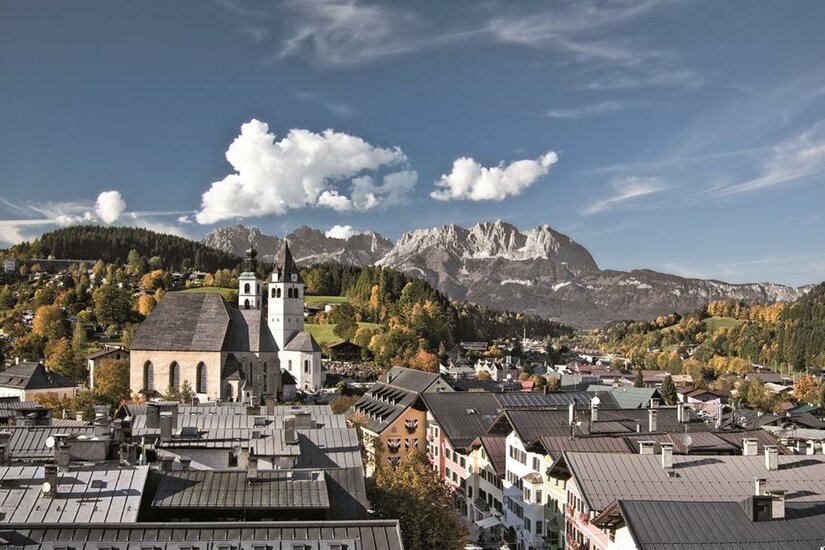Ortsansicht Kitzbühel Blick über die Dächer von Kitzbühel mit der Stadtpfarrkirche und dem Wilden Kaiser im Hintergrund.